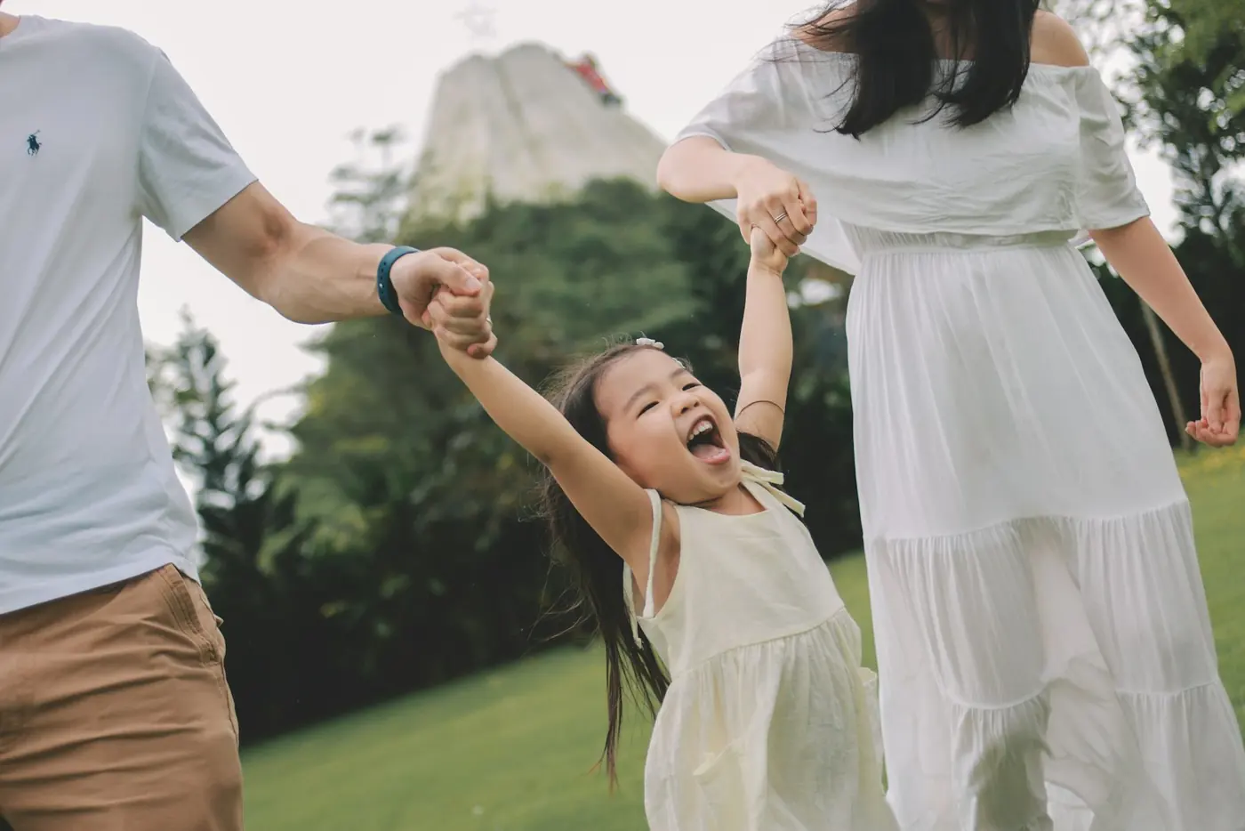 A family holding hands and laughing in a park